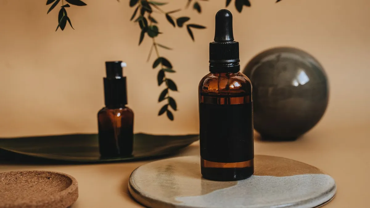 Amber glass dropper bottles of herbal liquid drops next to green leaves