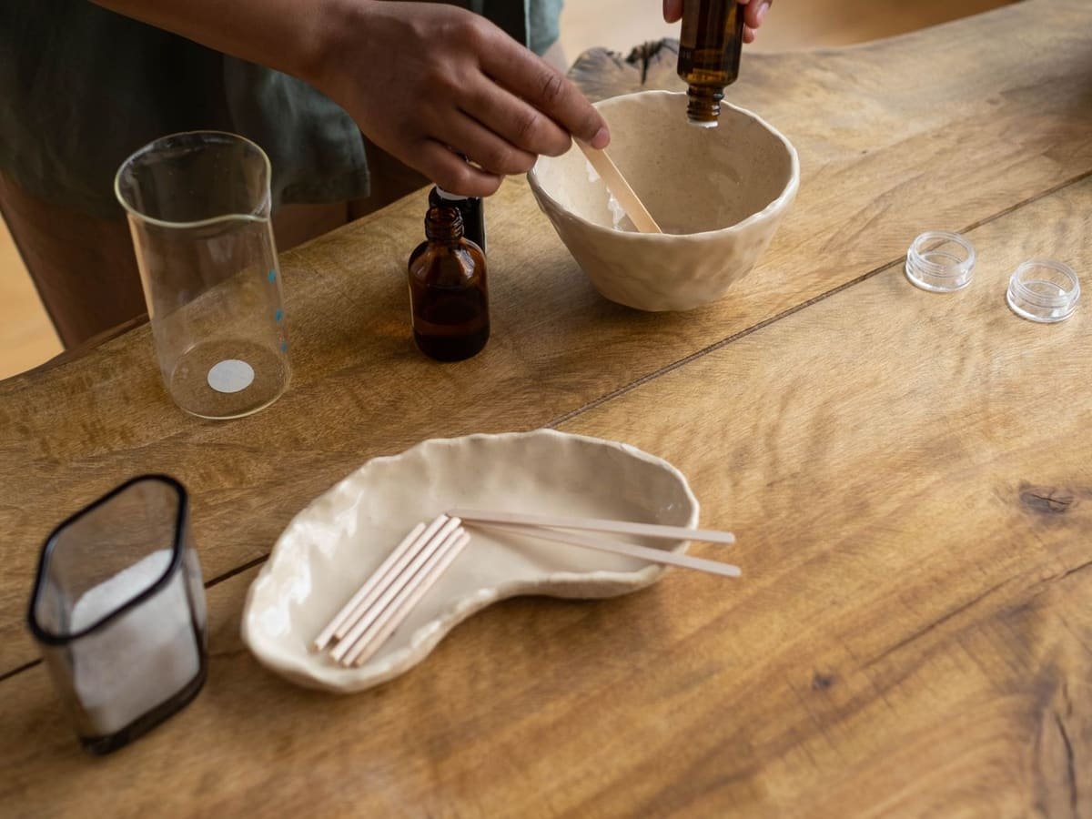 Essential oil bottles and a mixing bowl being prepared on a wooden table